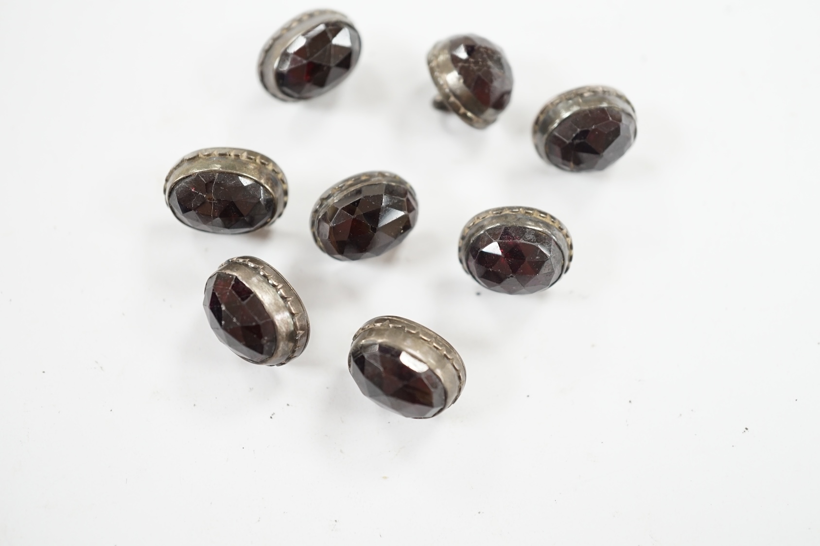 A set of eight 19th century white metal and facetted garnet set buttons, 12mm. Condition - fair but wear to the stones